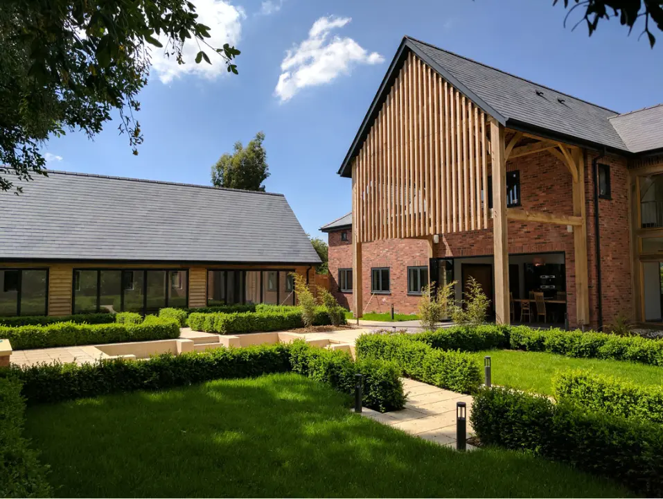 Modern residential property featuring red brick, timber cladding and oak framing, with landscaped gardens and a courtyard.
