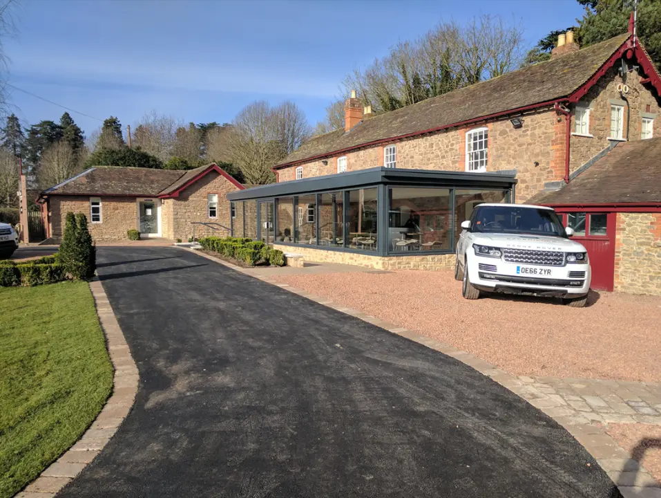 Traditional stone property with a contemporary glazed extension and landscaped driveway.