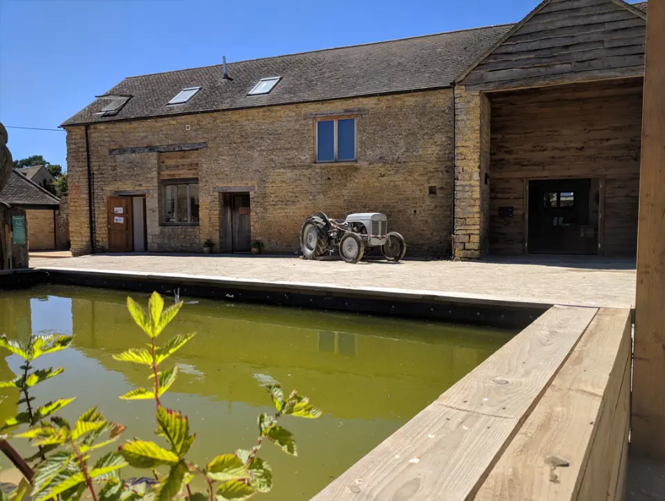 Restored stone barn buildings surrounding a courtyard and pond.