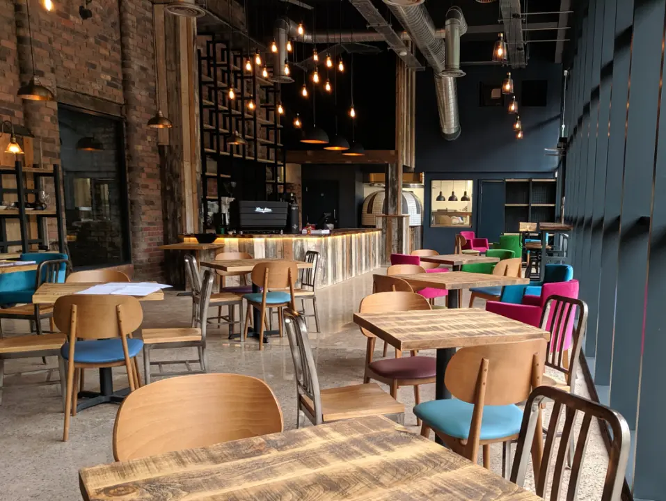 Contemporary café interior with exposed brickwork, timber finishes and colourful seating.