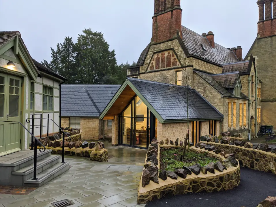 Contemporary glazed extension connecting historic stone buildings around a landscaped courtyard.